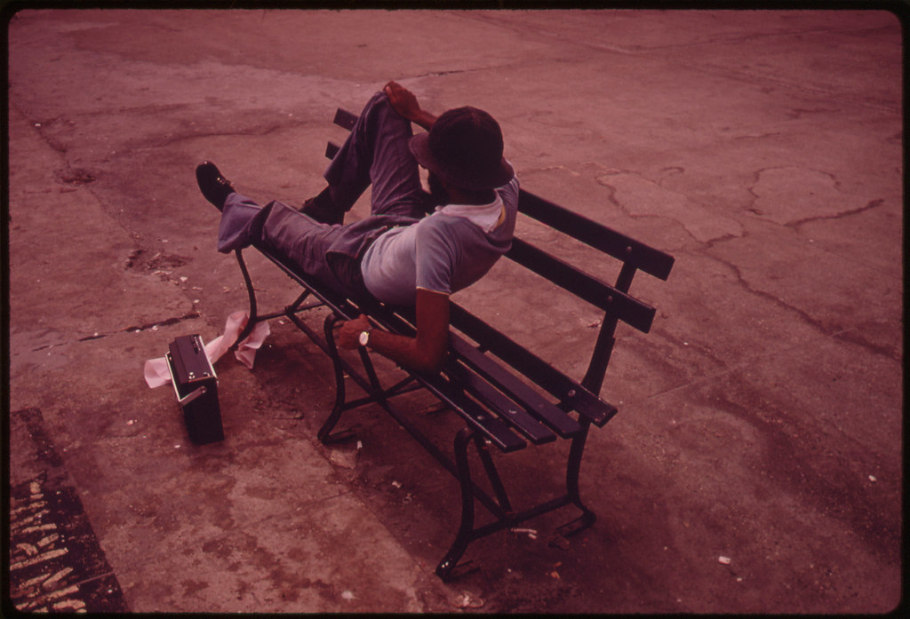 A man on a boardwalk bench with a portable radio, photographed in July 1974.